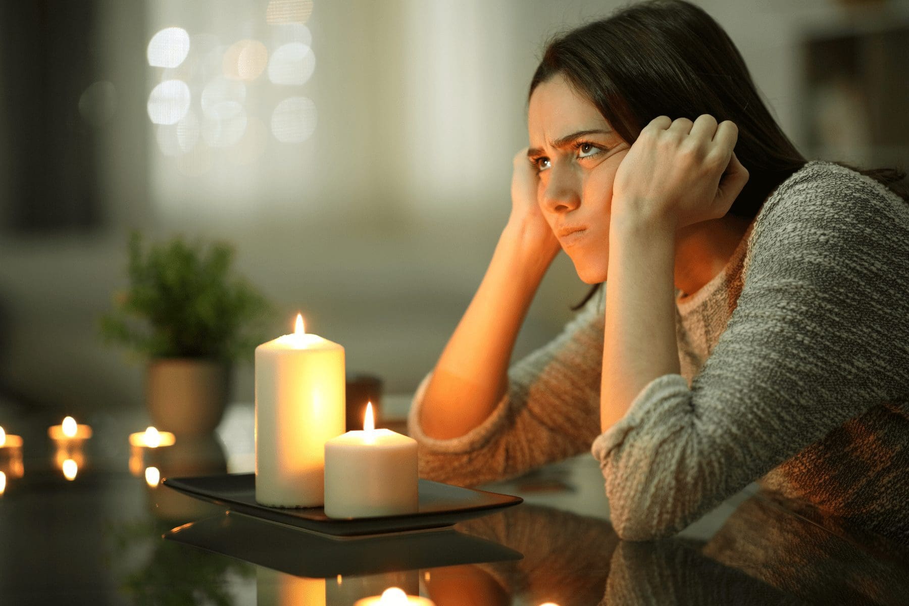woman sitting in a dark restaurant because of a power outage, with candles lit