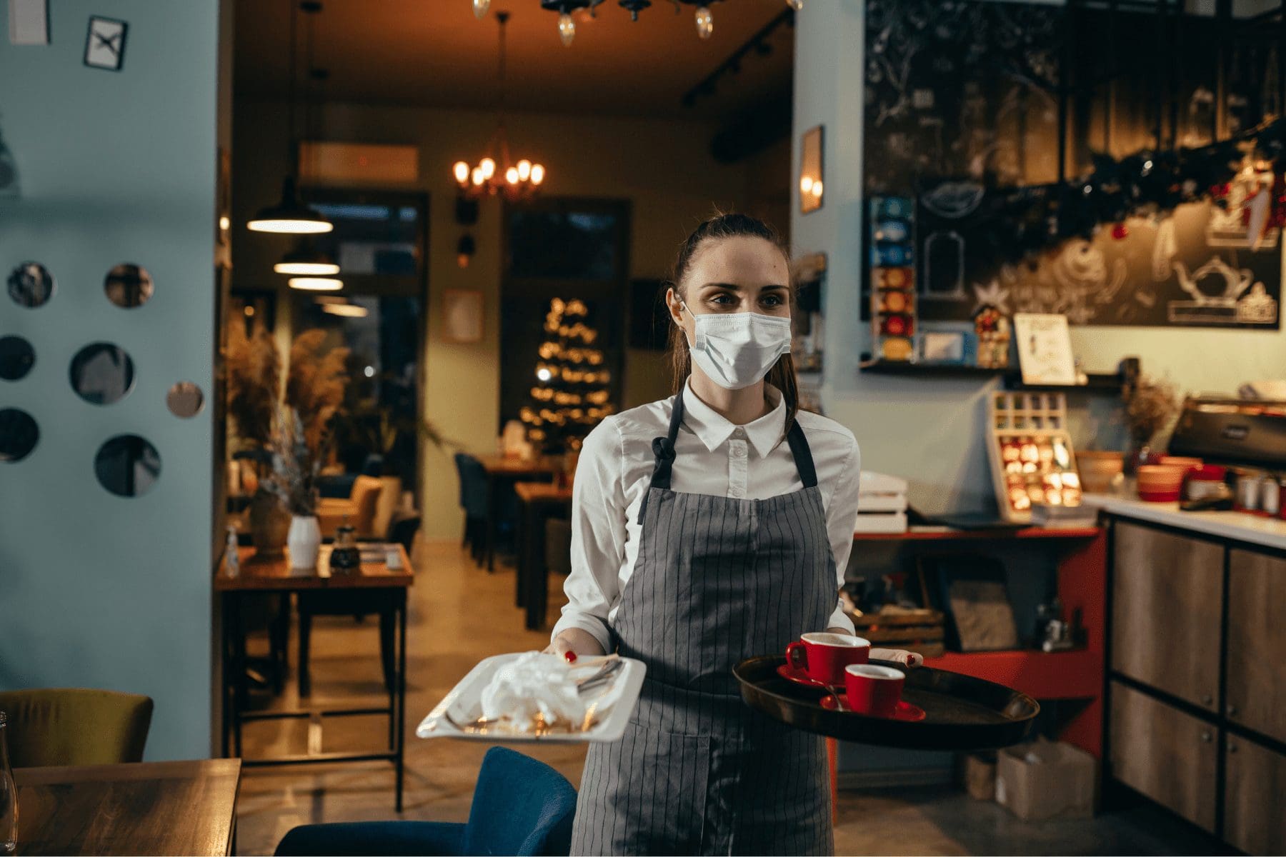 a restaurant employee serving food while wearing a mask