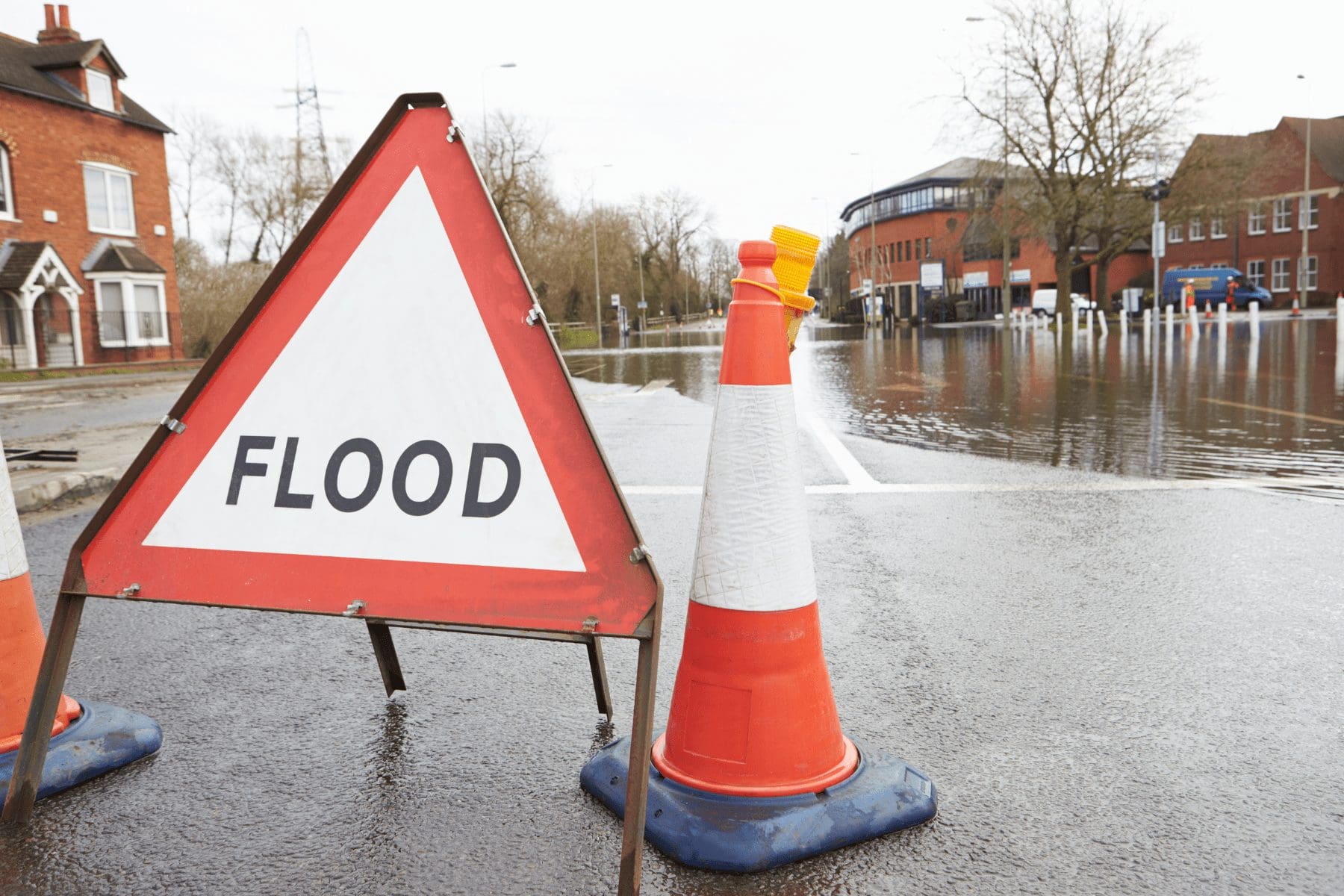 a flood sign near a commercial building illustrating the need for dic insurance